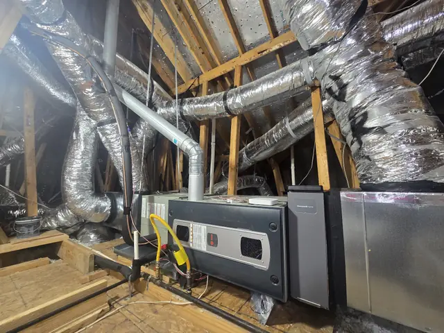 Wide view of a completed attic changeout with a new furnace, media filter cabinet and freshly sealed supply plenum